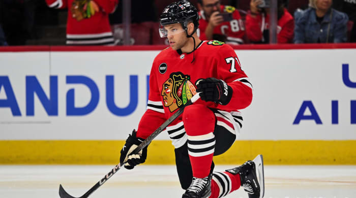Blackhawks forward Taylor Hall kneels on the ices before a game.